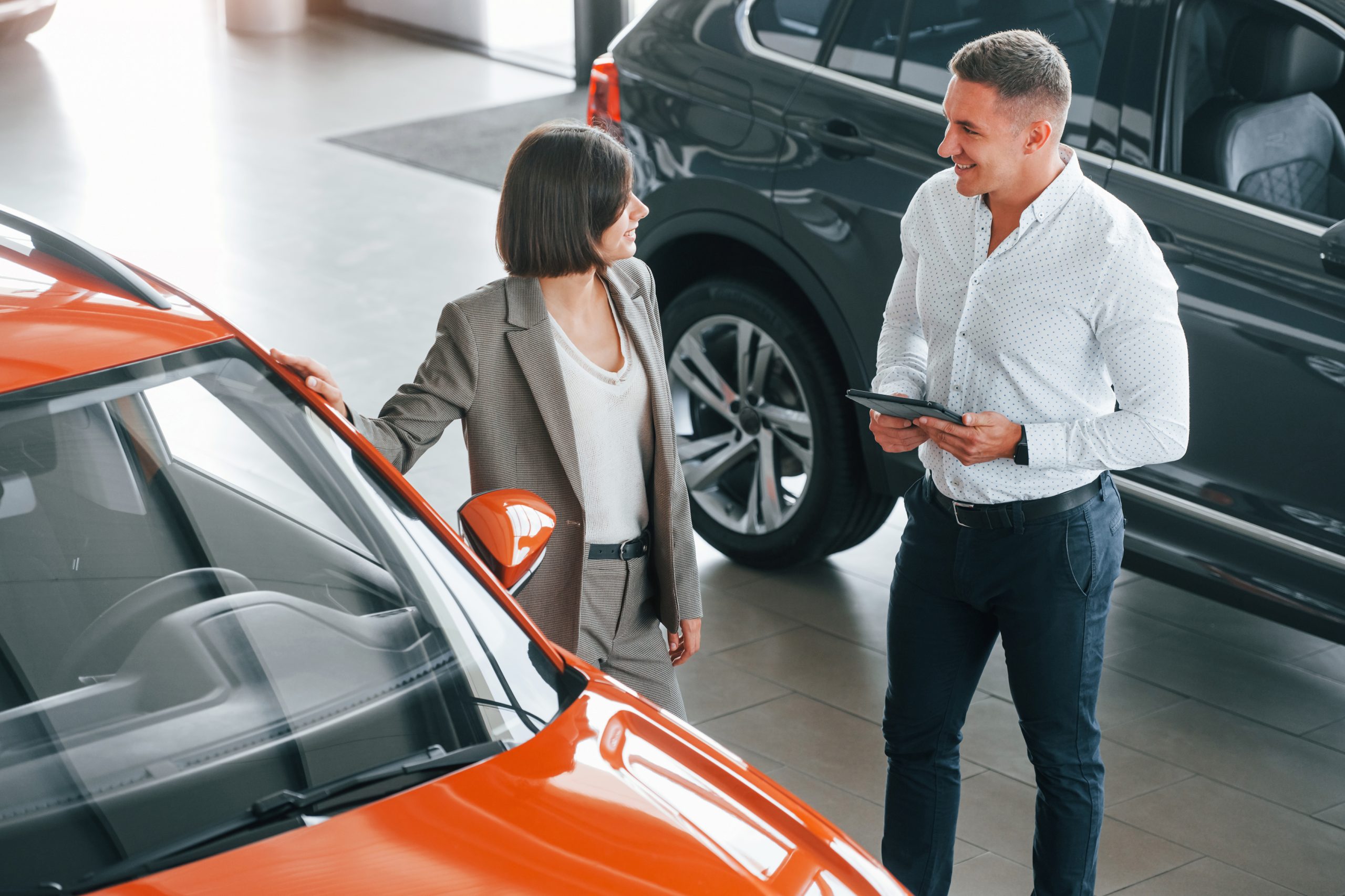 View from above. Man in formal wear helping customer with choice of the automobile