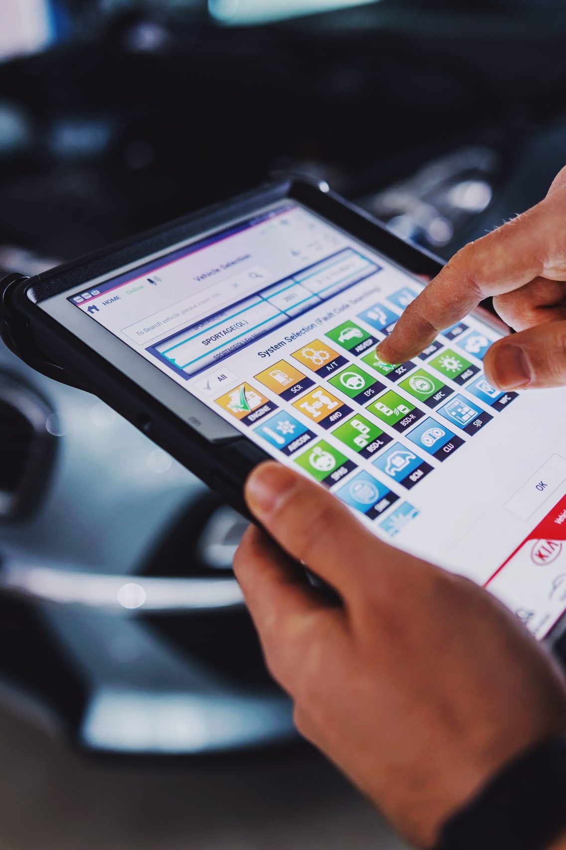 Mechanic using tablet for diagnosing a car issue. Garage of car salon interior.